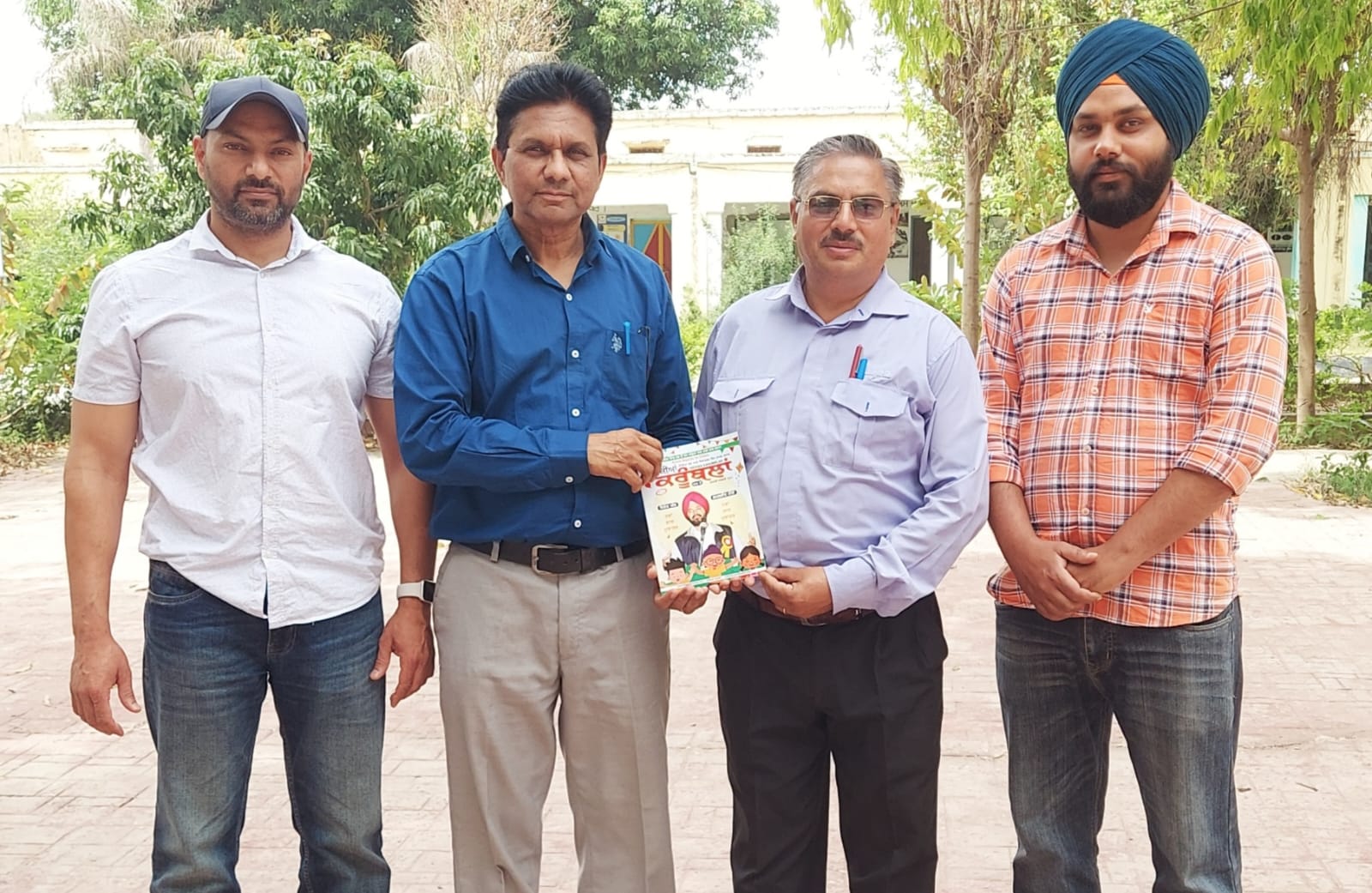 Baljinder Mann, editor of Nikkian Krumbals, presenting a set of books to Sukhwinder Singh, Harkamalpreet Singh and Kuljit Singh, teachers of Government High School Kukadan.